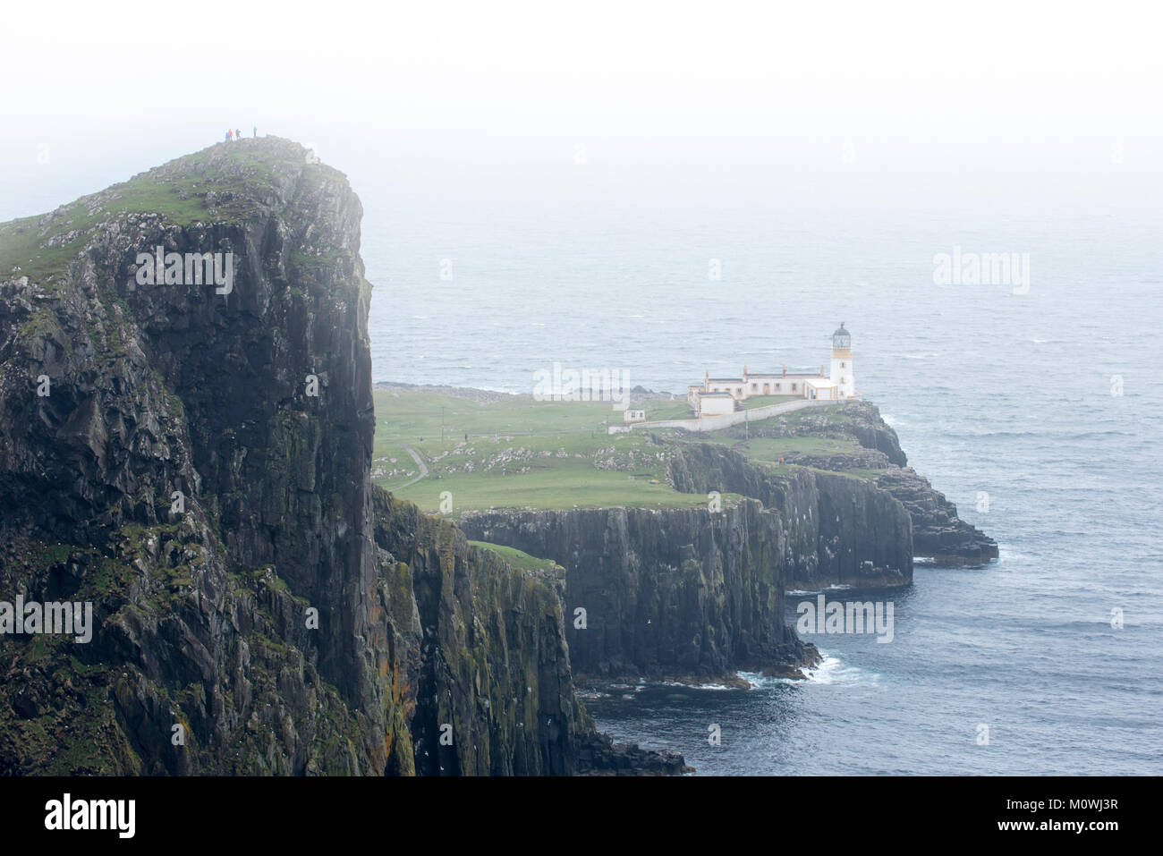 Les promeneurs sur la falaise regardant Neist Point Lighthouse dans la brume sur l'île de Skye, Hébrides intérieures, Highlands, Scotland, UK Banque D'Images