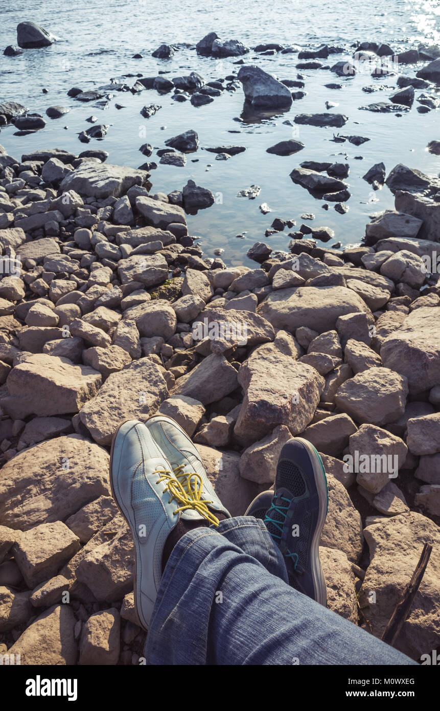 Les pieds mâles et femelles dans les chaussures de sport sur les pierres brutes. Voyages en famille lifestyle, photo verticale Banque D'Images