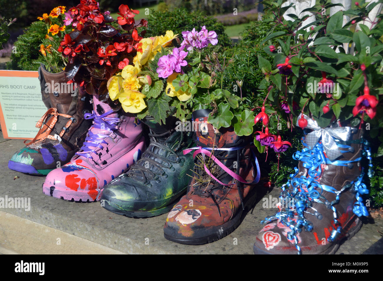 Vieux Bottes colorés recyclés dans les semoirs à jusqu'à un mur à RHS Garden Harlow Carr,, Harrogate, Yorkshire. UK. Banque D'Images