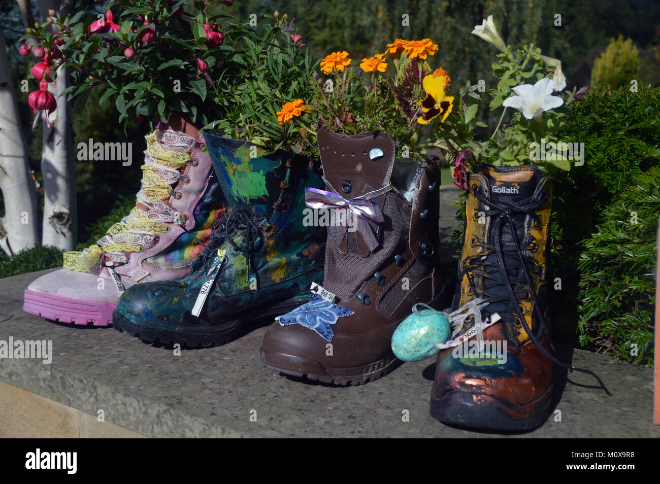 Vieux Bottes colorés recyclés dans les semoirs à jusqu'à un mur à RHS Garden Harlow Carr,, Harrogate, Yorkshire. UK. Banque D'Images