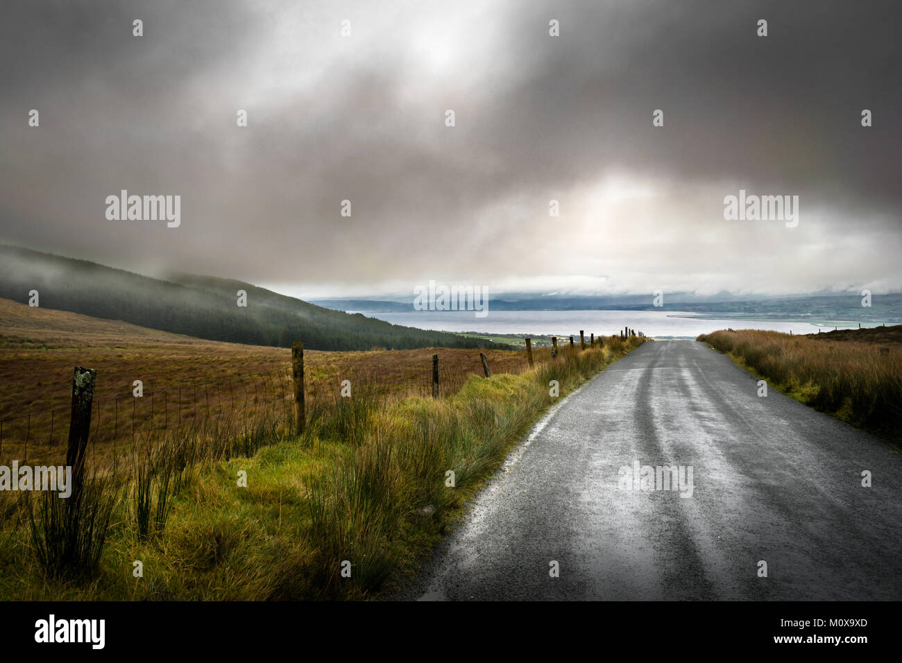 Route de montagne à distance en Irlande avec les nuages de pluie à basse altitude. Banque D'Images