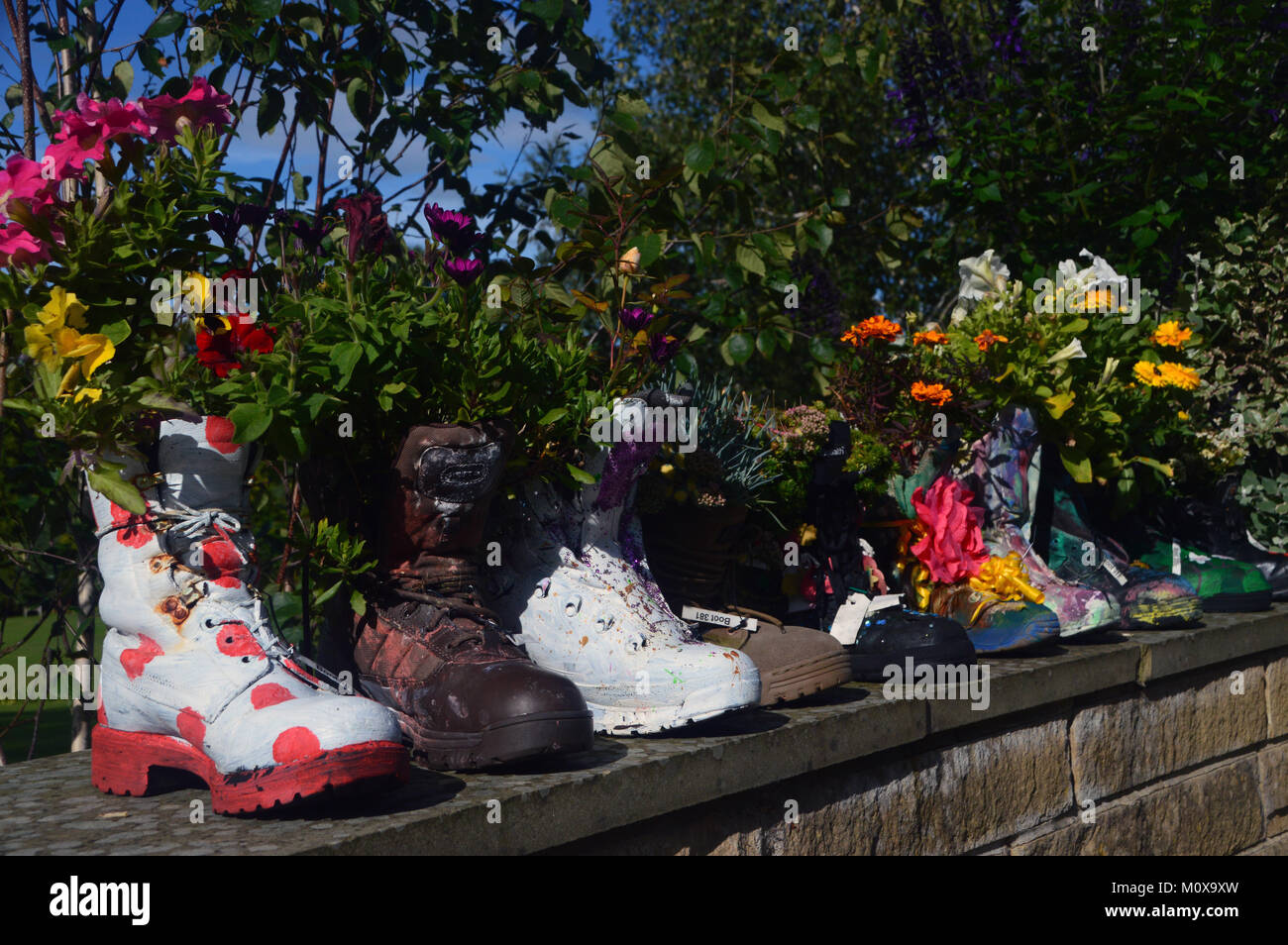Vieux Bottes colorés recyclés dans les semoirs à jusqu'à un mur à RHS Garden Harlow Carr,, Harrogate, Yorkshire. UK. Banque D'Images