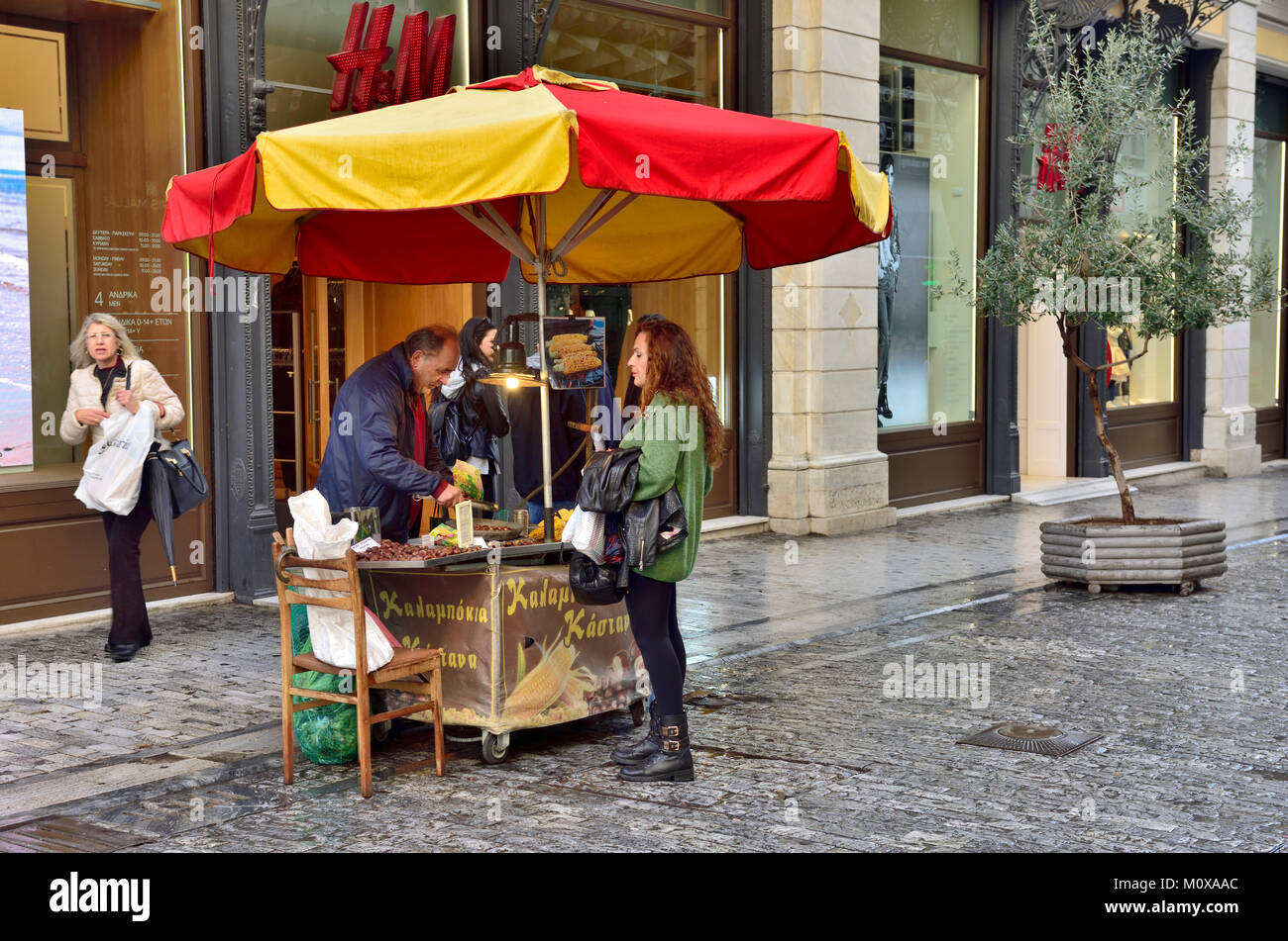 Vendeur alimentaire avec parapluie colorés sur son portable panier gril à charbon de vendre des épis de maïs grillés, Emou street, Athènes Banque D'Images