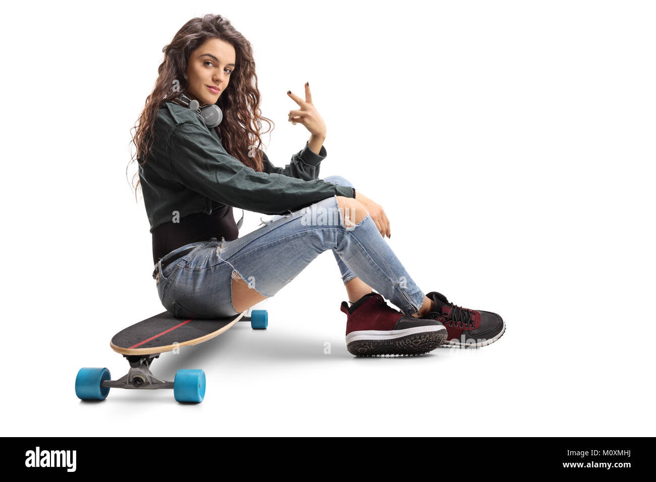 Teenage girl sitting on un longboard et faisant un geste de paix isolé sur fond blanc Banque D'Images