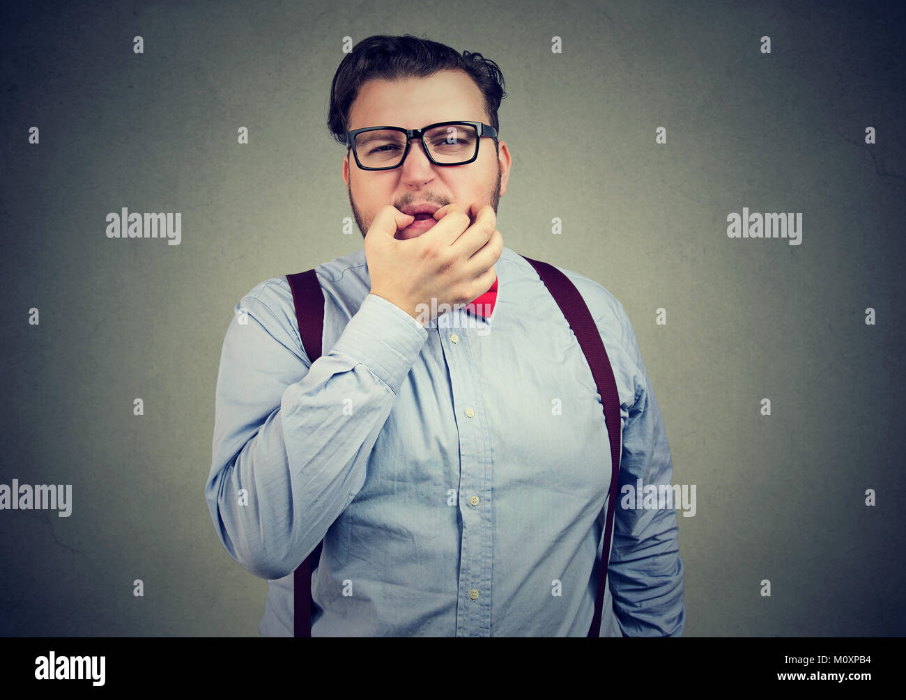 Jeune homme en costume officiel bully sifflet à huis clos sur fond gris. Banque D'Images