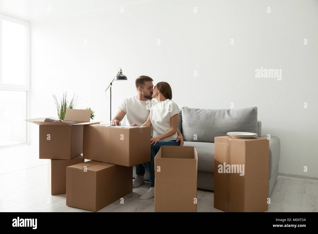 Couple sitting on sofa in living room with boxes Banque D'Images