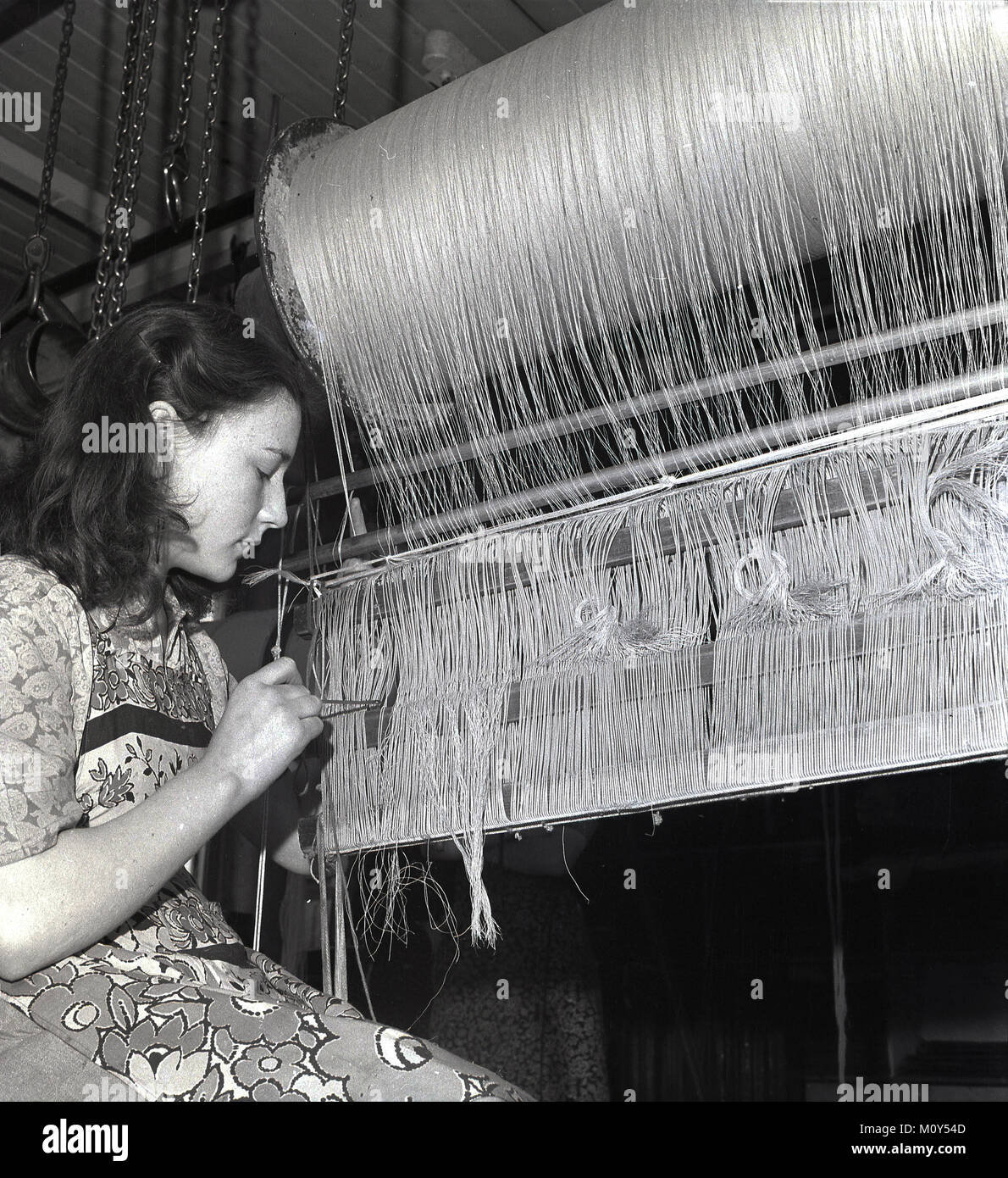 Années 1950, historiques, les jeunes femmes weaver travaille sur un tissage de lin lomb, centre d'un des fils, l'Irlande du Nord. Banque D'Images