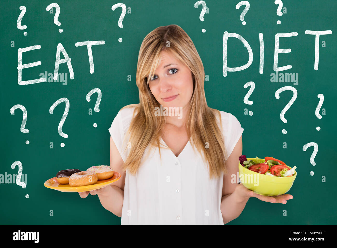 Jeune femme confuse faisant Choix de manger des aliments sains et malsains Banque D'Images