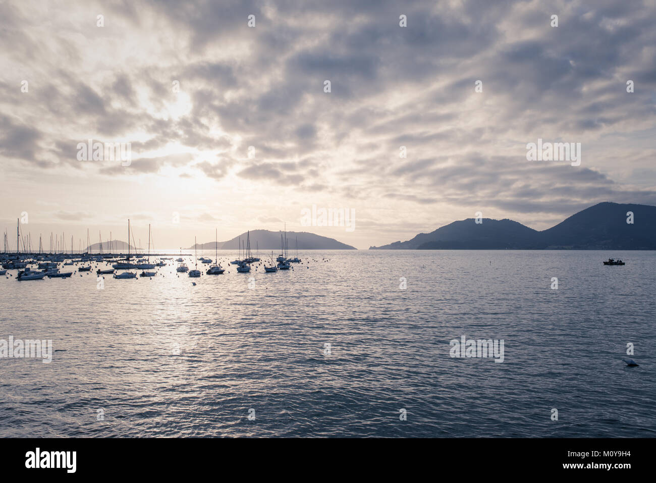 Italien méditerranéen calme sur la mer du petit port avec plusieurs bateaux dans la distance et les montagnes en arrière-plan au coucher du soleil. Vintage Retro mat Banque D'Images