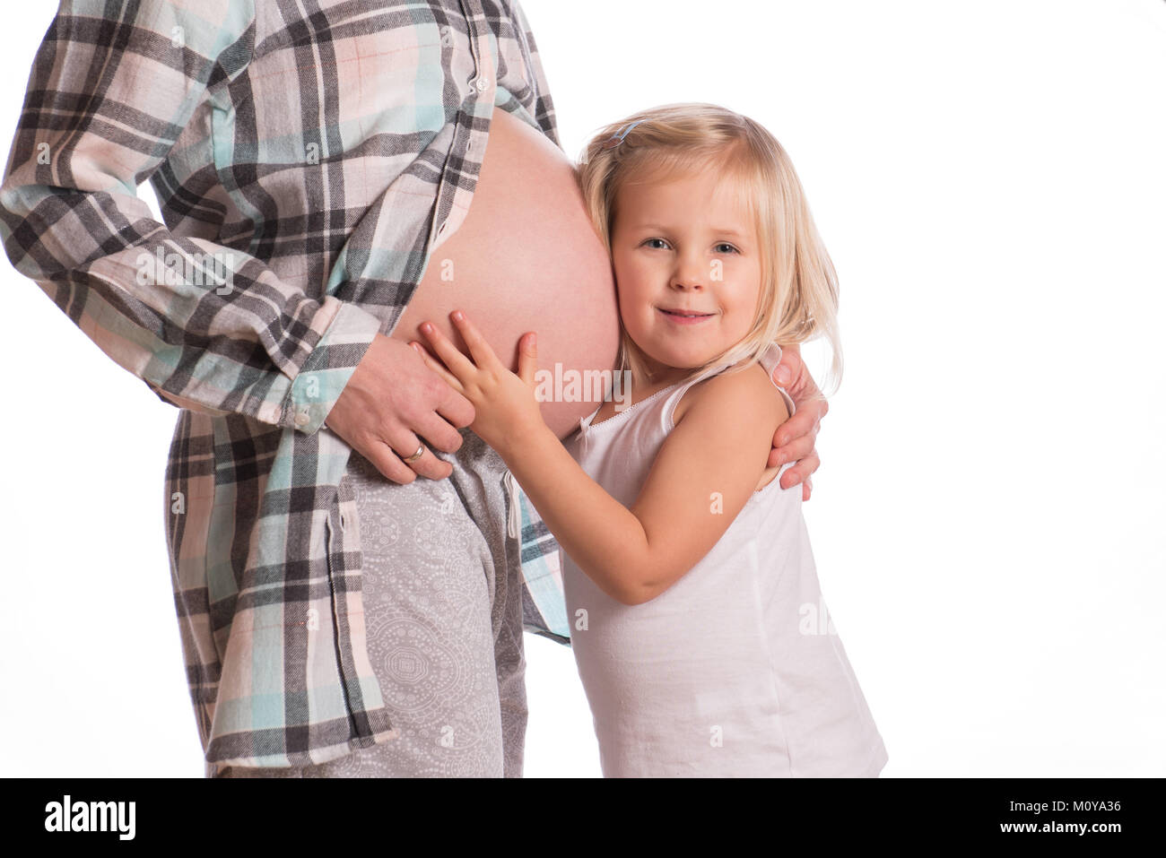 Petite fille embrassant sa mère enceinte ventre et regardant la caméra Banque D'Images