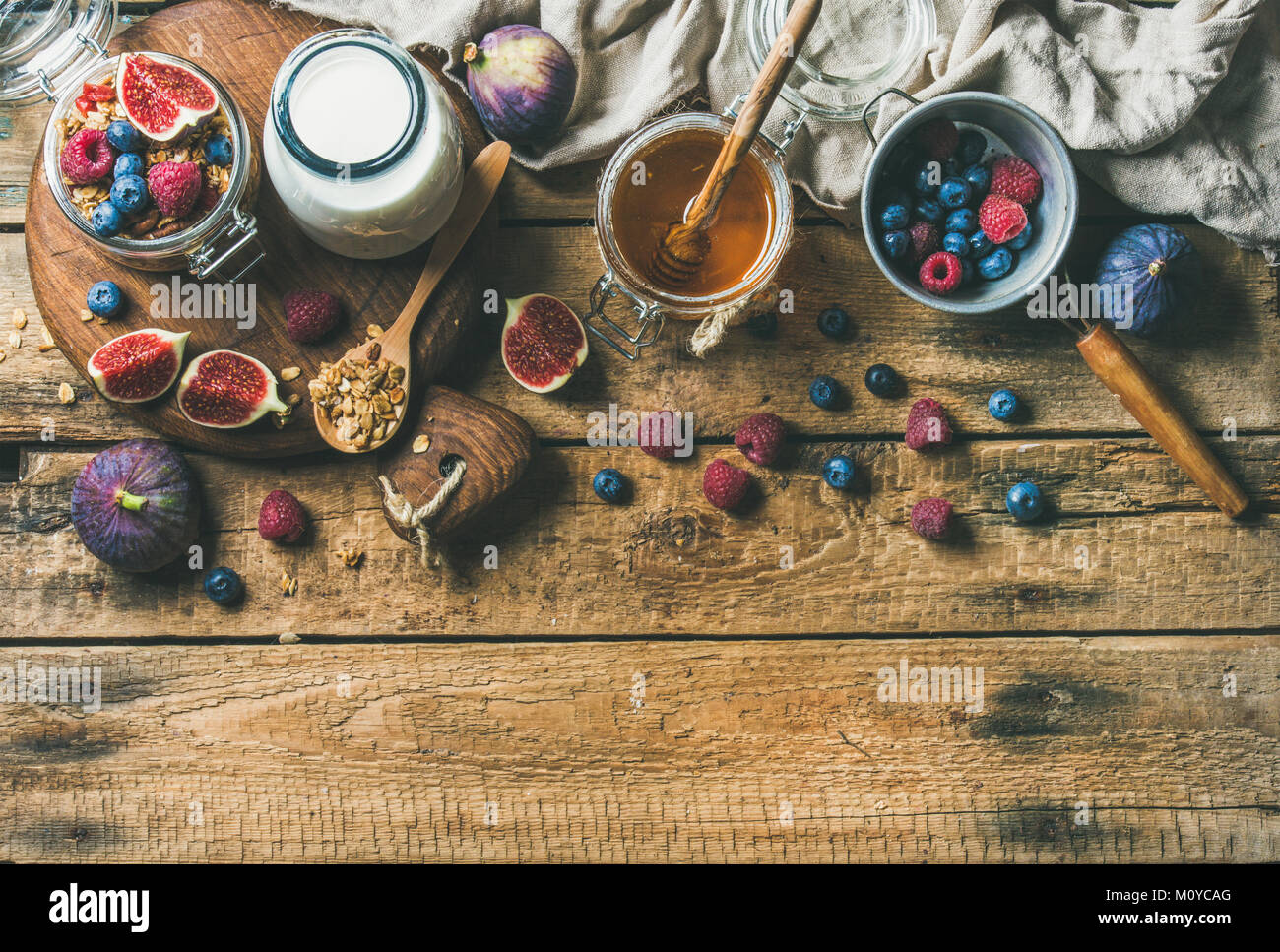 Petit-déjeuner végétalien sain. Granola avoine avec de l'eau en bouteille de lait d'amande, miel, fruits et baies sur fond de table en bois rustique, copy space, haut Banque D'Images