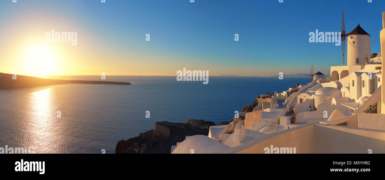 Coucher de soleil sur l'île de Santorin en Grèce. L'église traditionnelle, les appartements et les moulins à vent dans le village d''Oia, photo panoramique. Banque D'Images