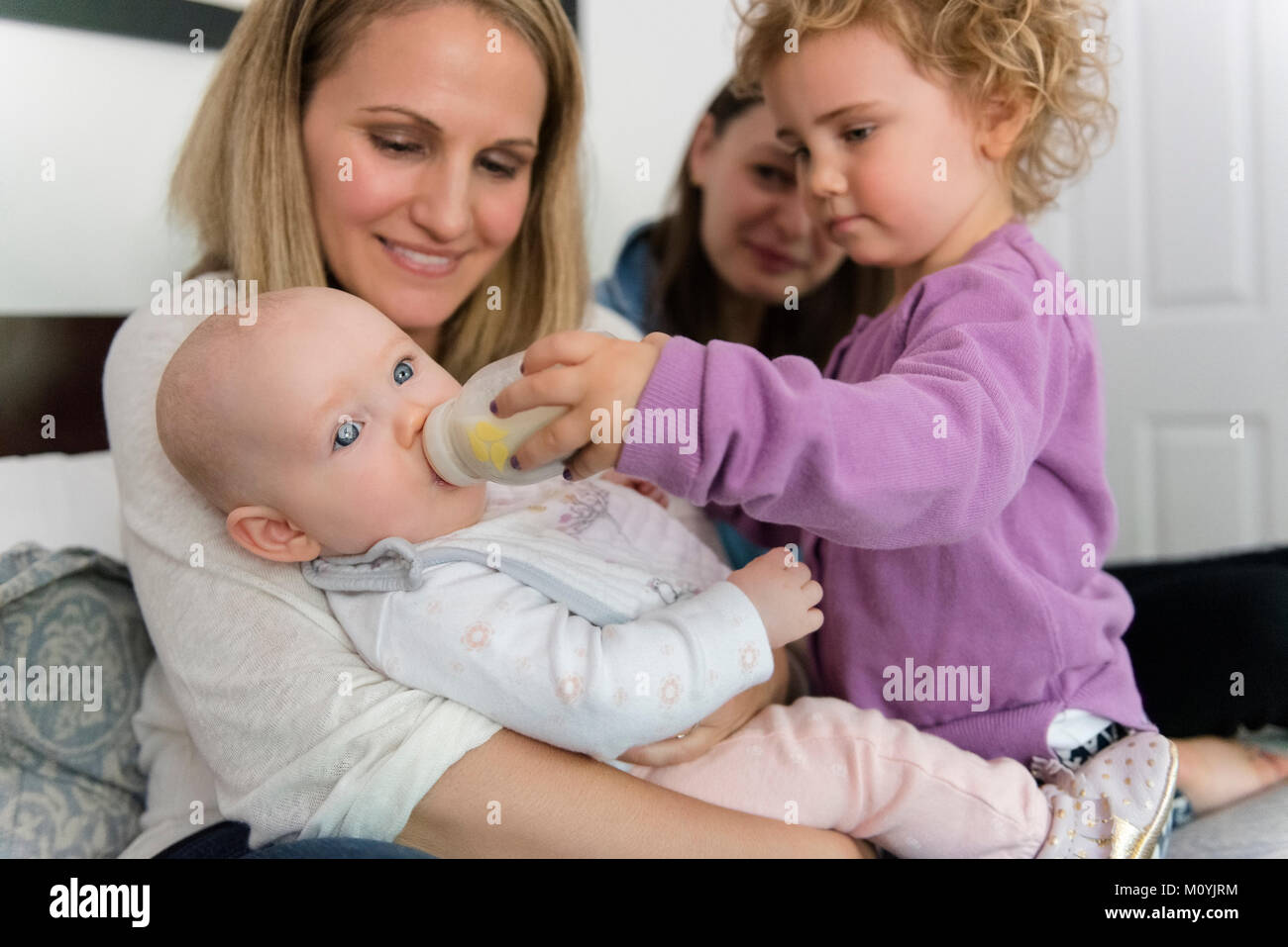 Caucasian girl feeding bottle pour baby sister Banque D'Images