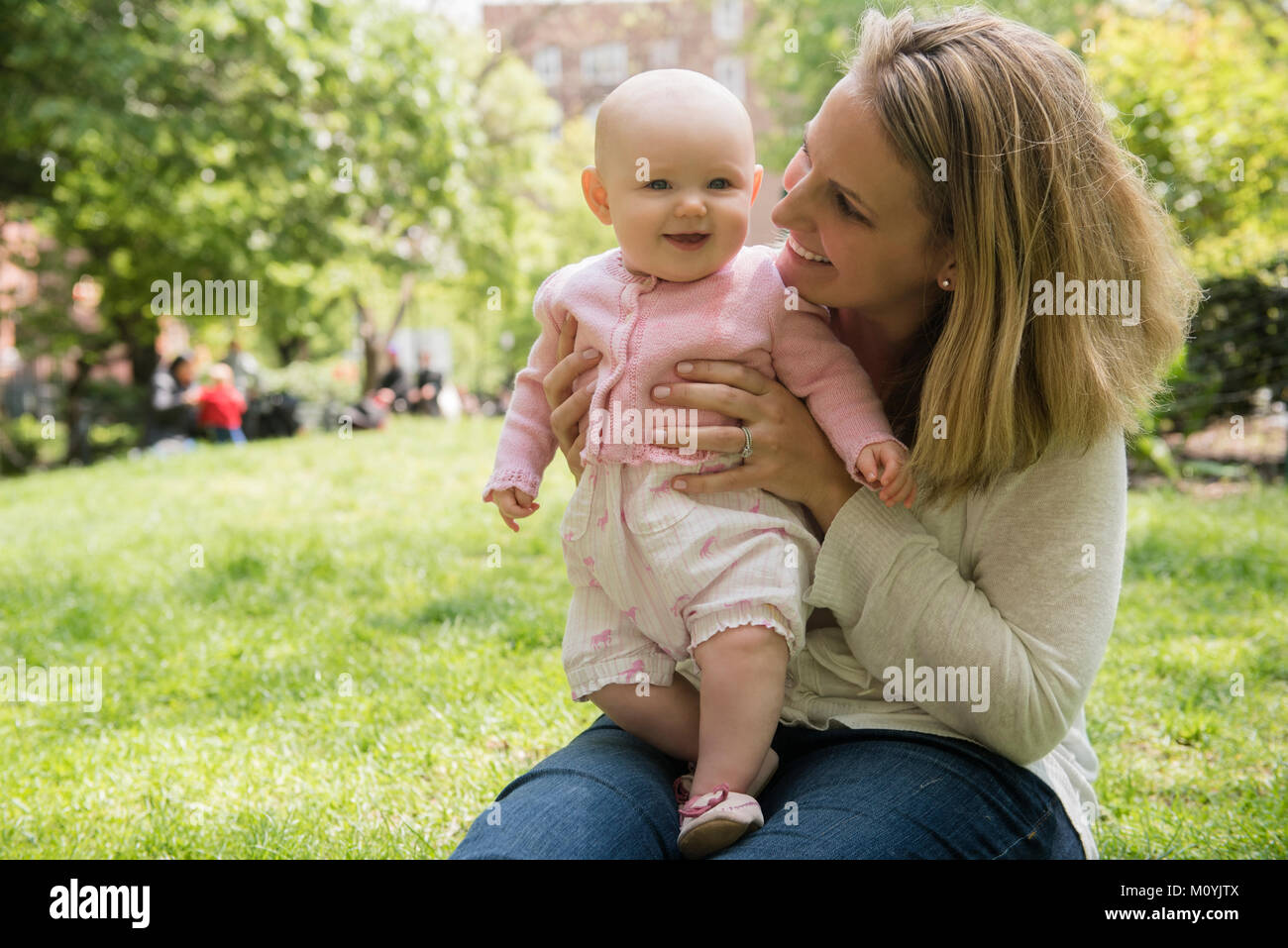 Portrait of Caucasian mother holding baby daughter in park Banque D'Images
