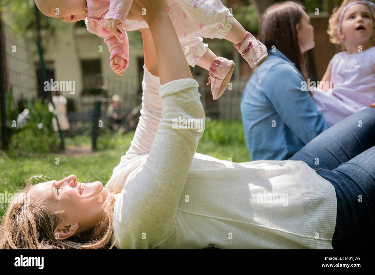 Portrait of woman laying in grass bébé fille de levage Banque D'Images