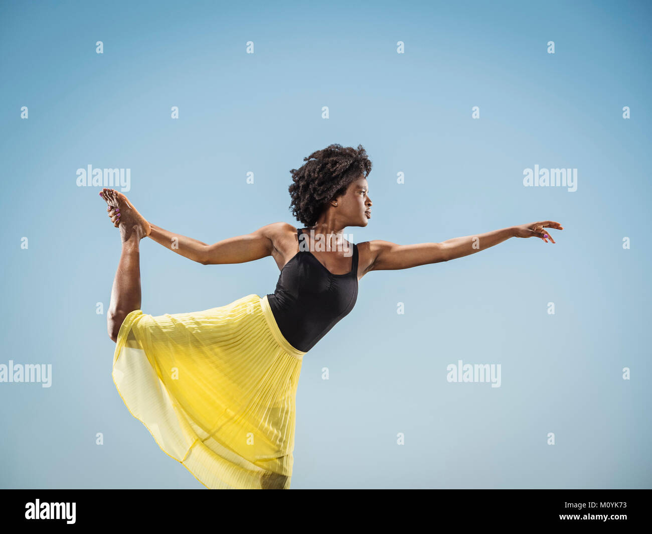 Femme Noir debout sur une jambe pied holding Banque D'Images