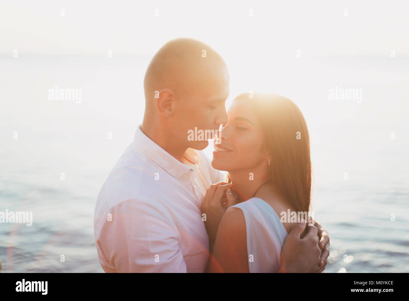 Caucasian couple hugging près de ocean at sunset Banque D'Images