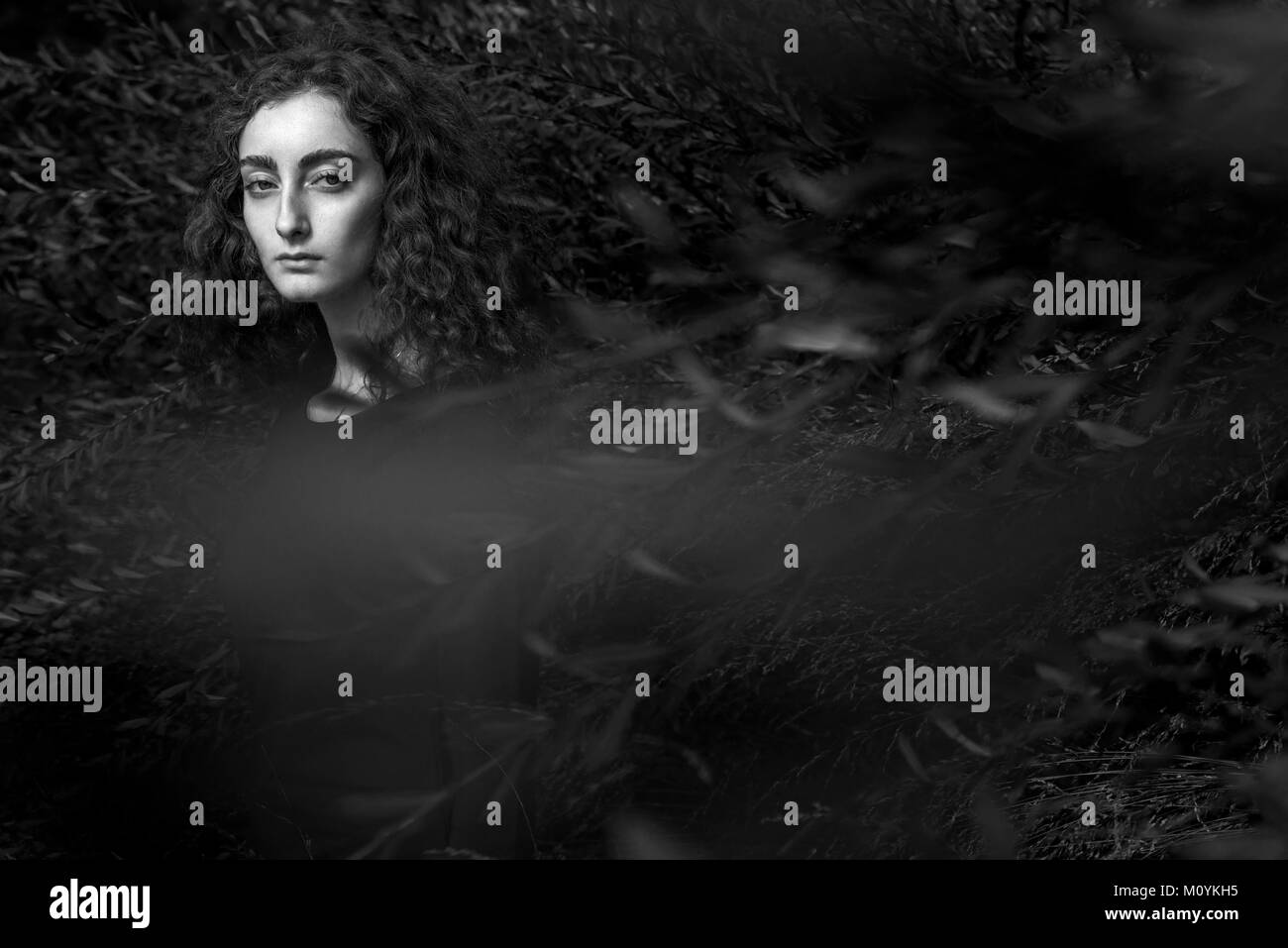 De graves Caucasian woman standing behind branches Banque D'Images