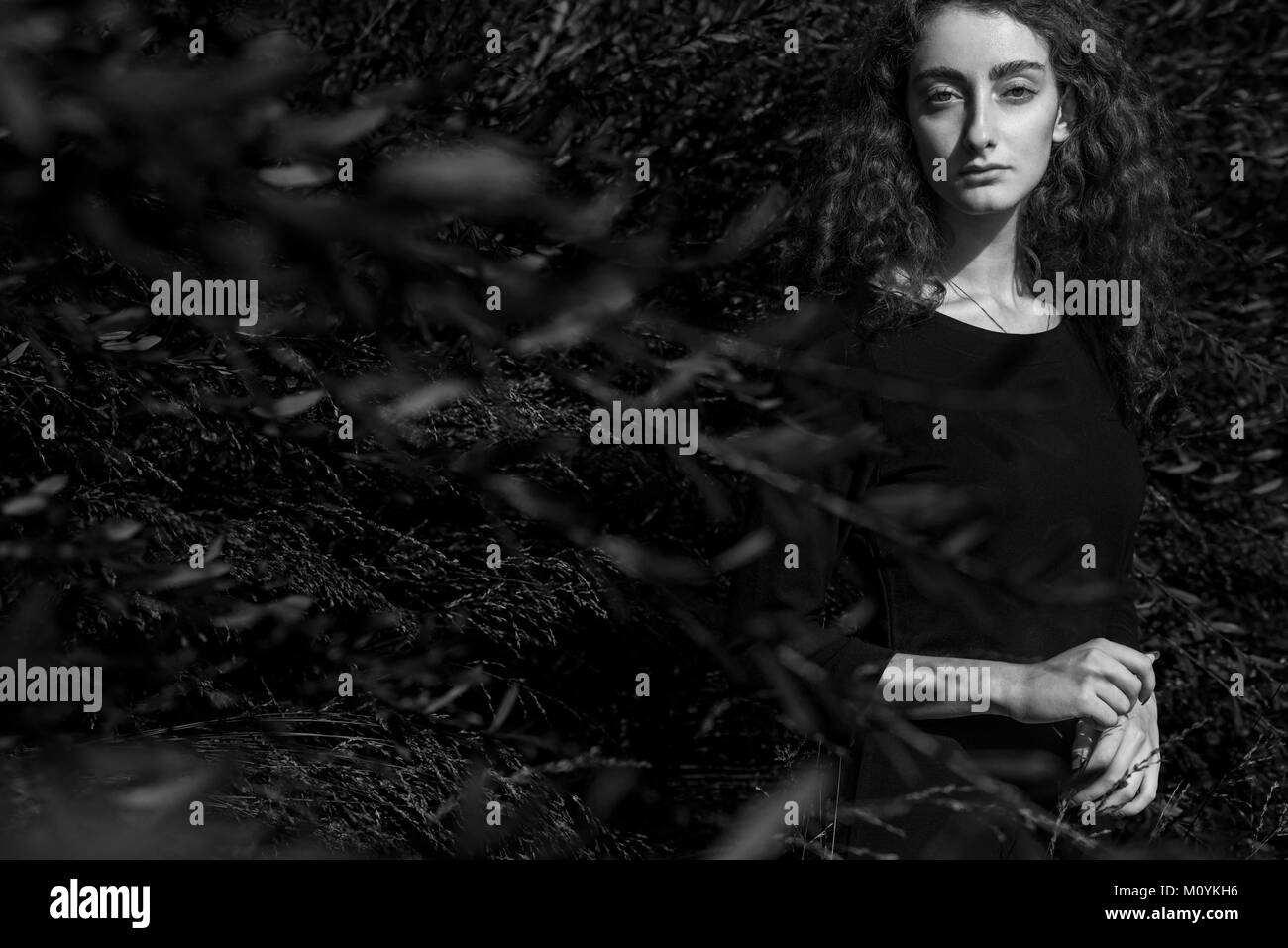 De graves Caucasian woman standing behind branches Banque D'Images