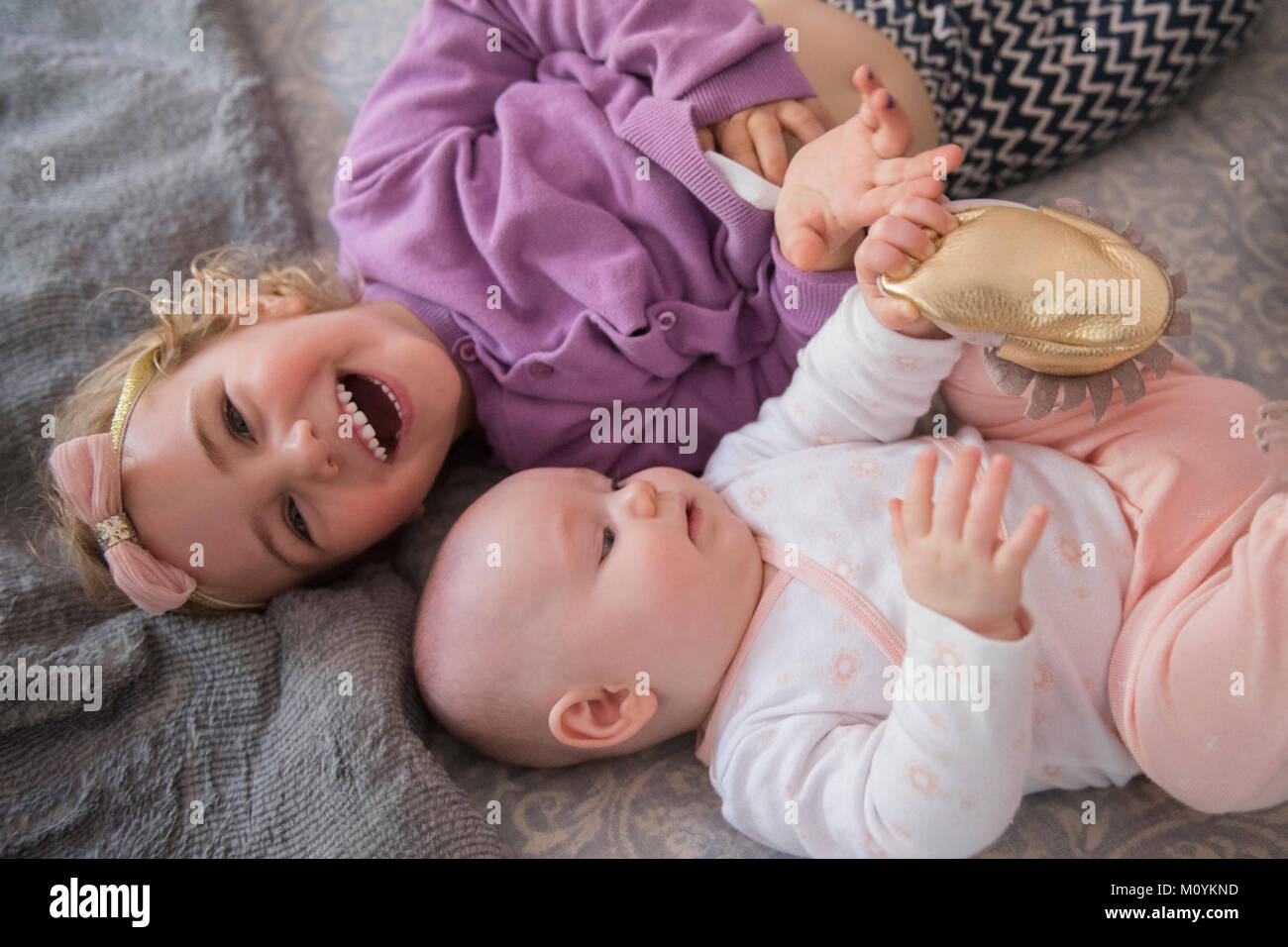 Caucasian girl laying on floor with baby sister Banque D'Images
