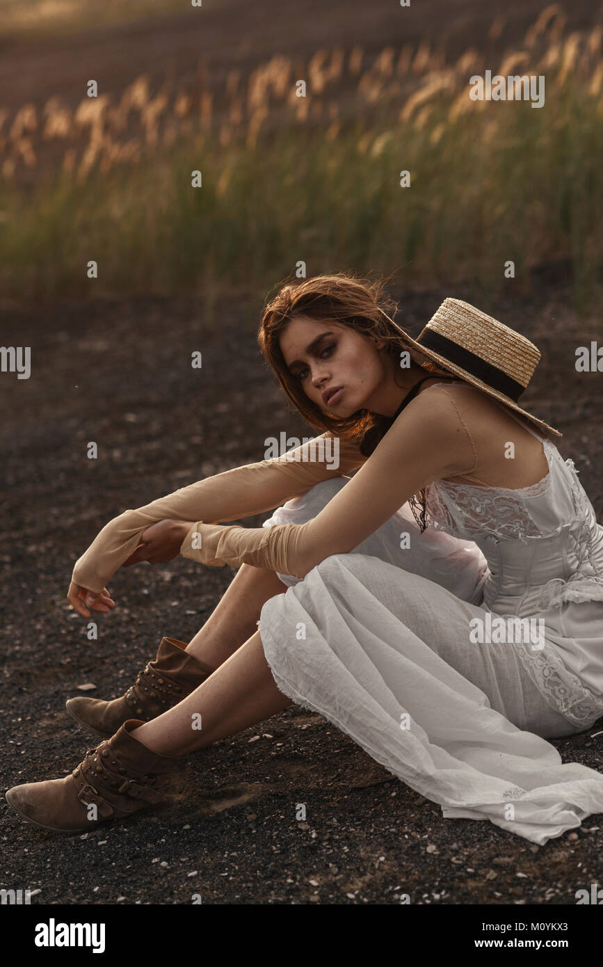 Sexy woman wearing white dress sitting in field Banque D'Images