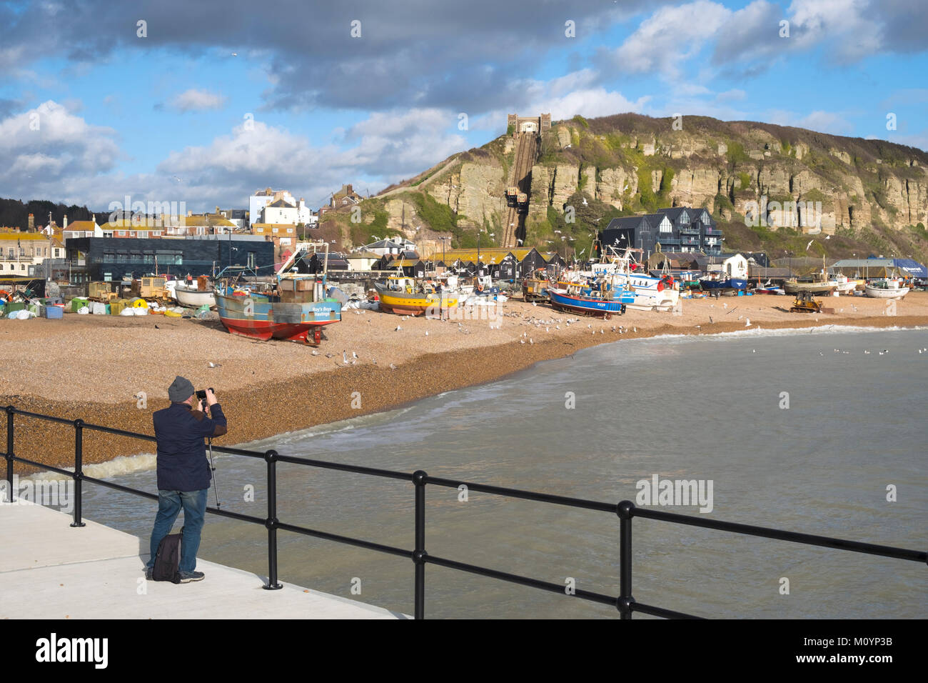 Près de la vieille ville de Hastings plage des pêcheurs ; un photographe saisit la scène pittoresque de mouettes tournoyant autour des bateaux de pêche, East Sussex, UK Banque D'Images