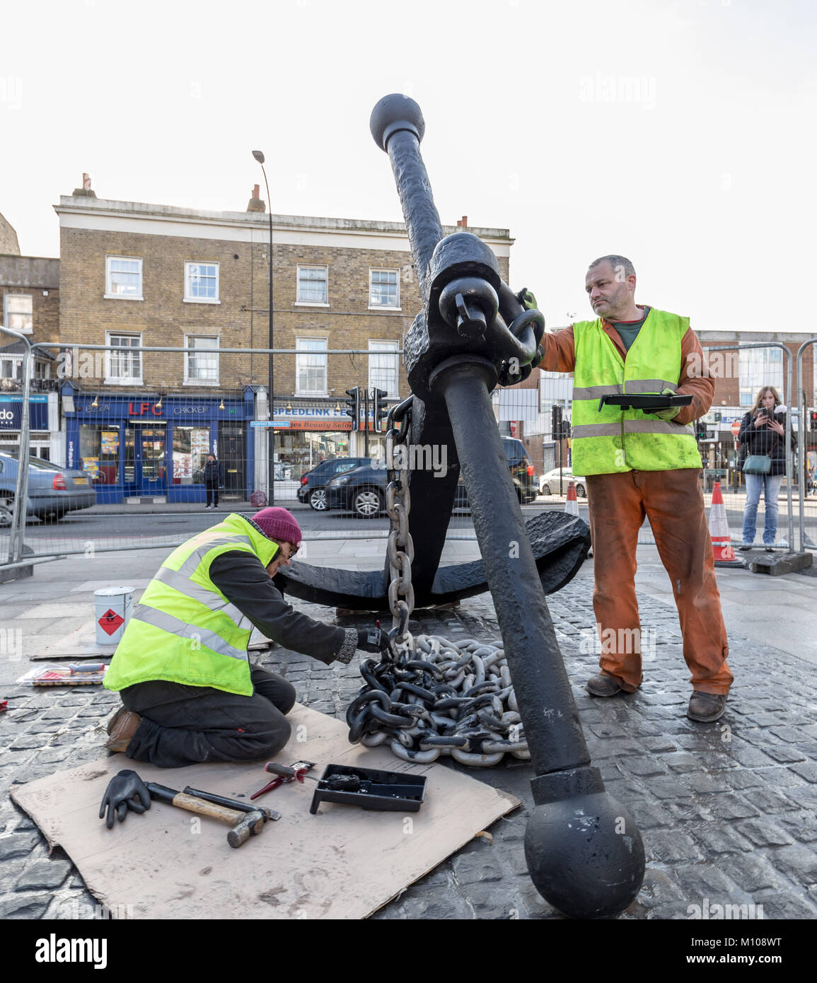 Londres, Royaume-Uni. 25 Jan, 2018. L'emblématique Deptford ancre est finalement remis à sa place d'origine à l'extrémité sud de Deptford High Street après avoir été retiré en 2013 pour des travaux de réaménagement de la rue. Vu ici à peindre sur sa nouvelle base pavée peu après avoir été soulevée. L'ancre fait partie de la riche histoire maritime de Deptford. Crédit : Guy Josse/Alamy Live News Banque D'Images