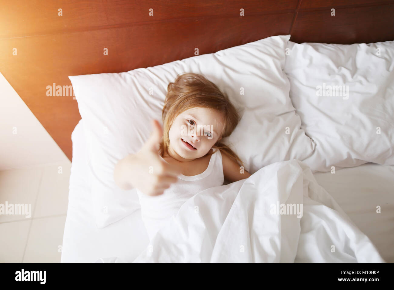 Portrait de petite fille show Thumbs up, telles que le dépôt à l'accueil  lit blanc aux beaux bon matin Photo Stock - Alamy