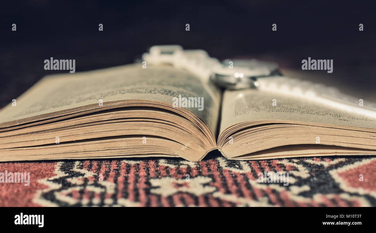 Livre ouvert et réveil blanc sur elle, sur un tapis Banque D'Images