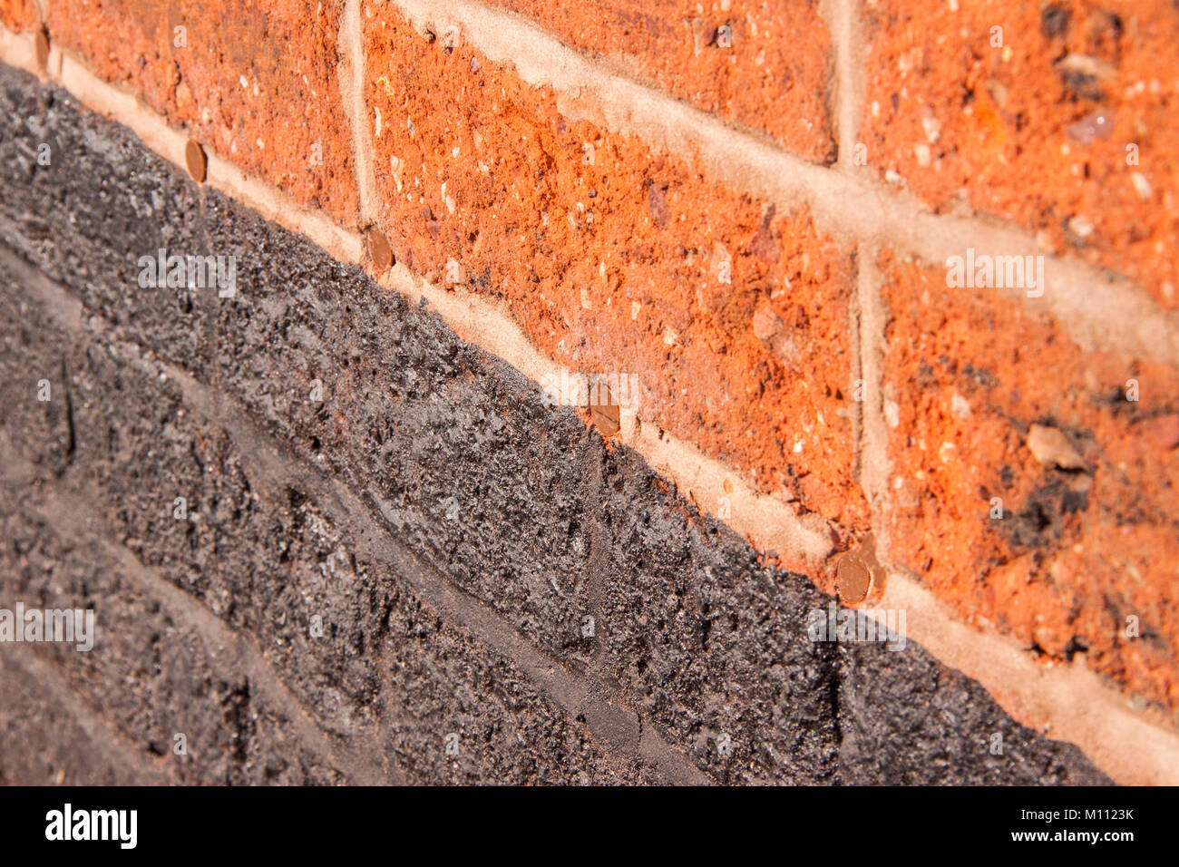 Mur de brique rouge montrant trous remplis plus d'après une preuve humide cours a été injecté dans la maçonnerie. Banque D'Images