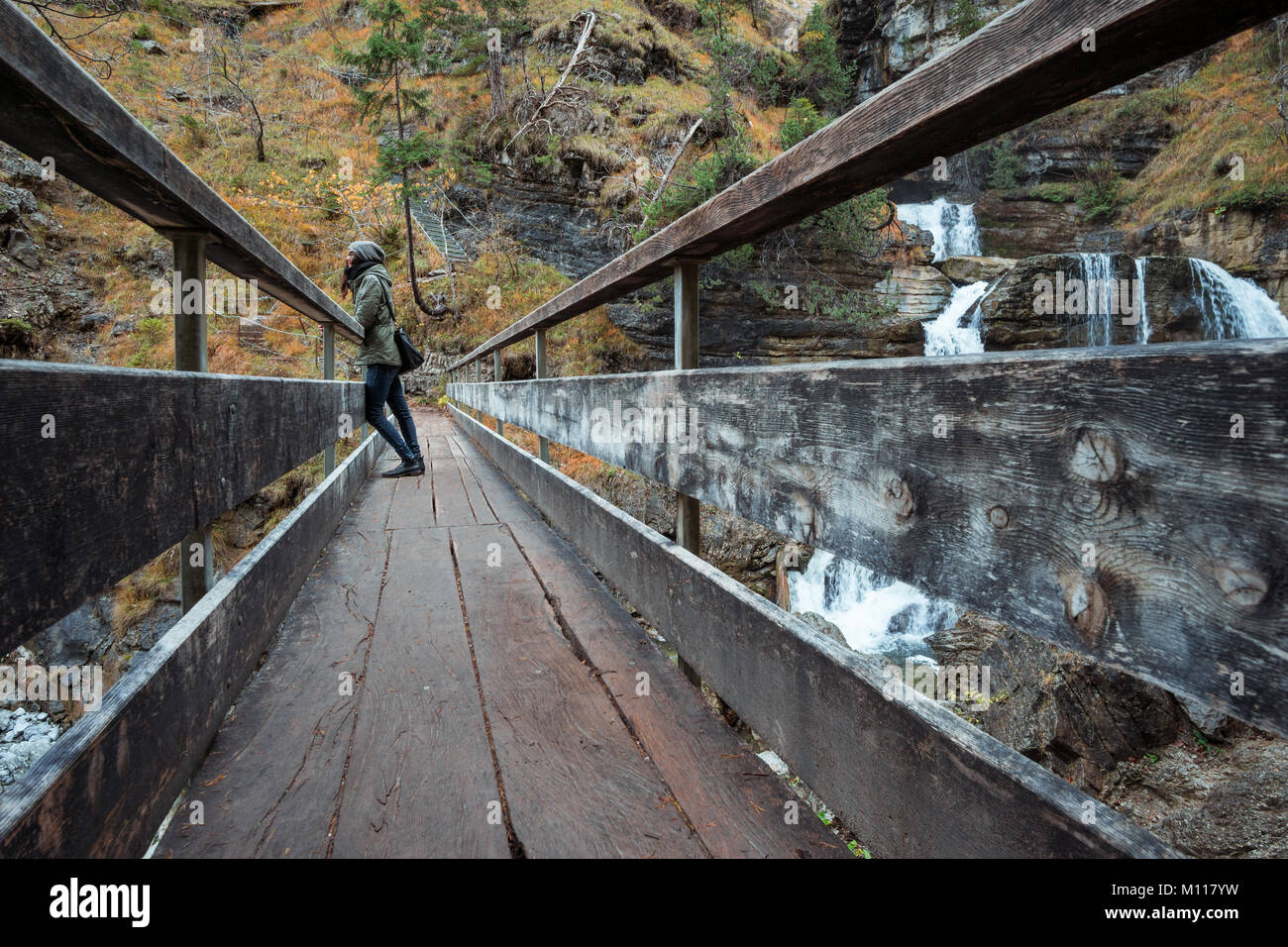 Femme debout sur un pont à l'Kuhfluchtwasserfall allemand - Cascade - près de les Alpes allemandes alors que l'automne. Banque D'Images