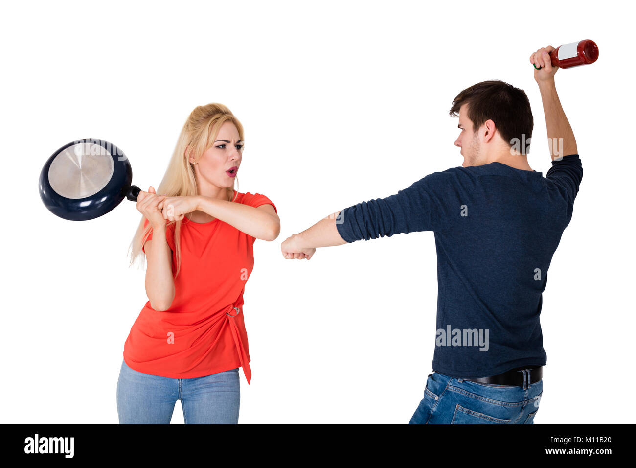 Les jeunes en colère Couple Fighting avec poêle et bouteille Against White Background Banque D'Images