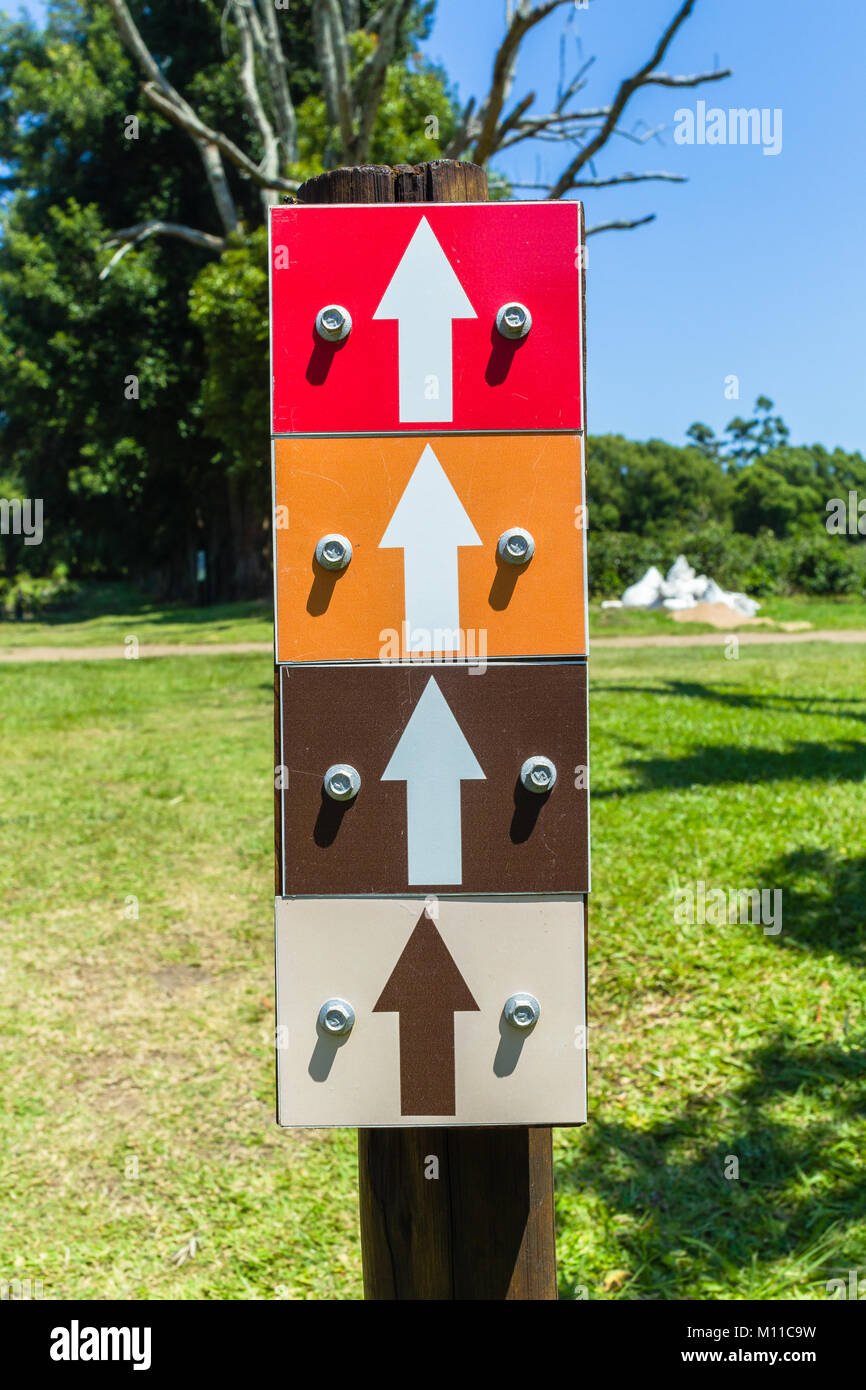 Quatre signes de flèche en rouge, orange, brun, beige,couleurs code pour les pistes de sport extérieur photo gros plan. Banque D'Images
