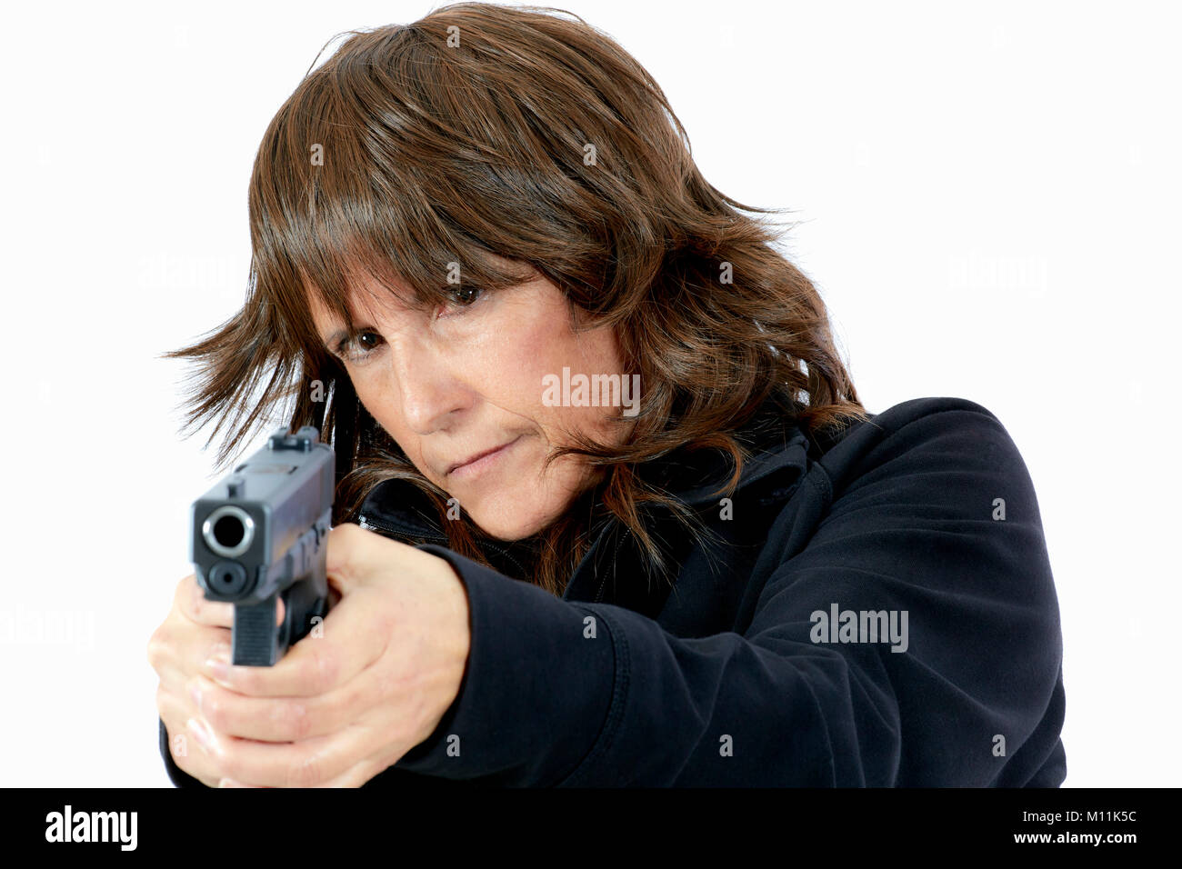 Belle femme d'âge moyen avec brown dégradées visant un pistolet isolated on white Banque D'Images