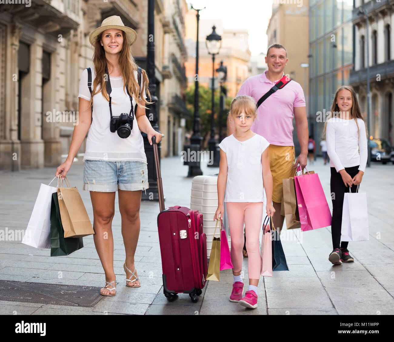 En toute sécurité avec une assurance voyage suisse famille de quatre personnes se promener avec assurance le long de la rue de la ville européenne Banque D'Images