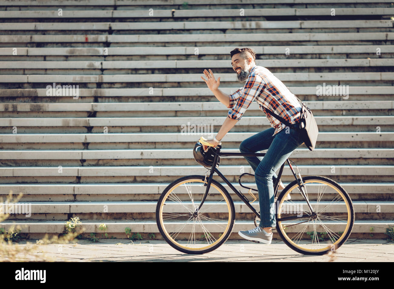 Handsome businessman occasionnels aller au travail en vélo. Il est riding bike et forme Bonjour. Banque D'Images