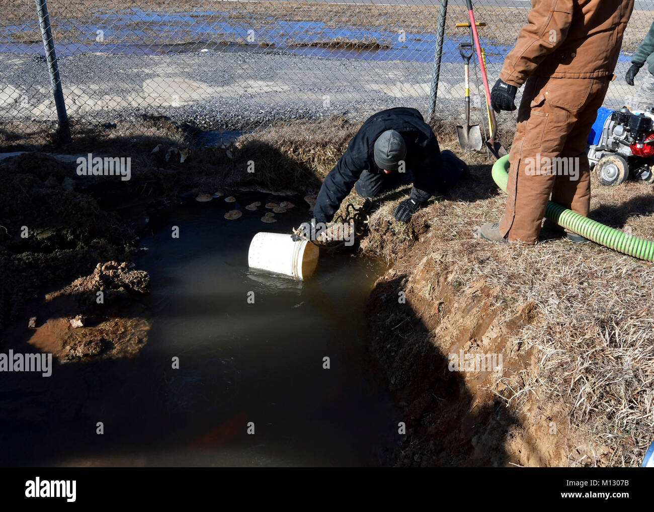 Les cadres supérieurs de l'US Air Force Airman Jimmy Huang, 51e Escadron de génie civil et de l'eau fossiles maintenance système, recueille l'eau à l'aide d'un godet à Osan Air Base, République de Corée, le 24 janvier 2018. Les députés de la 51e SCÉ a dû réparer une conduite d'eau souterraine qui a été endommagé en raison de temps froid. (U.S. Air Force Banque D'Images