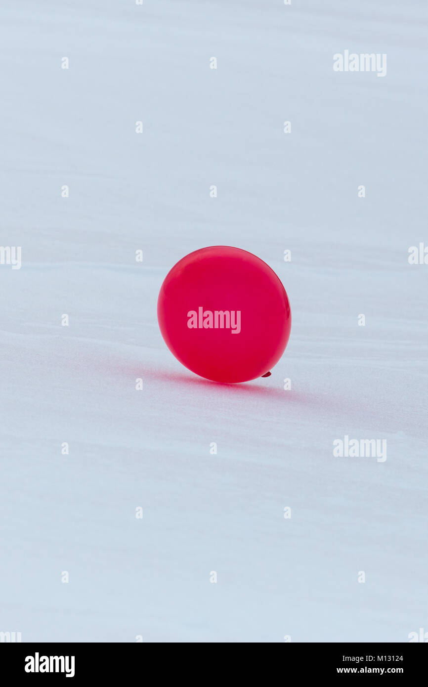 Un ballon rouge isolé sur blanc la masse de neige en hiver Banque D'Images