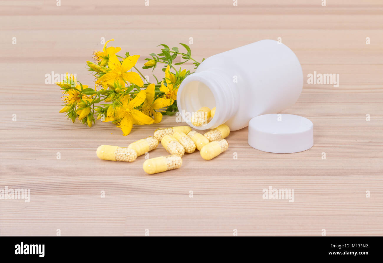 Fleurs de millepertuis et blanc contenant avec des médicaments le sol en bois Banque D'Images