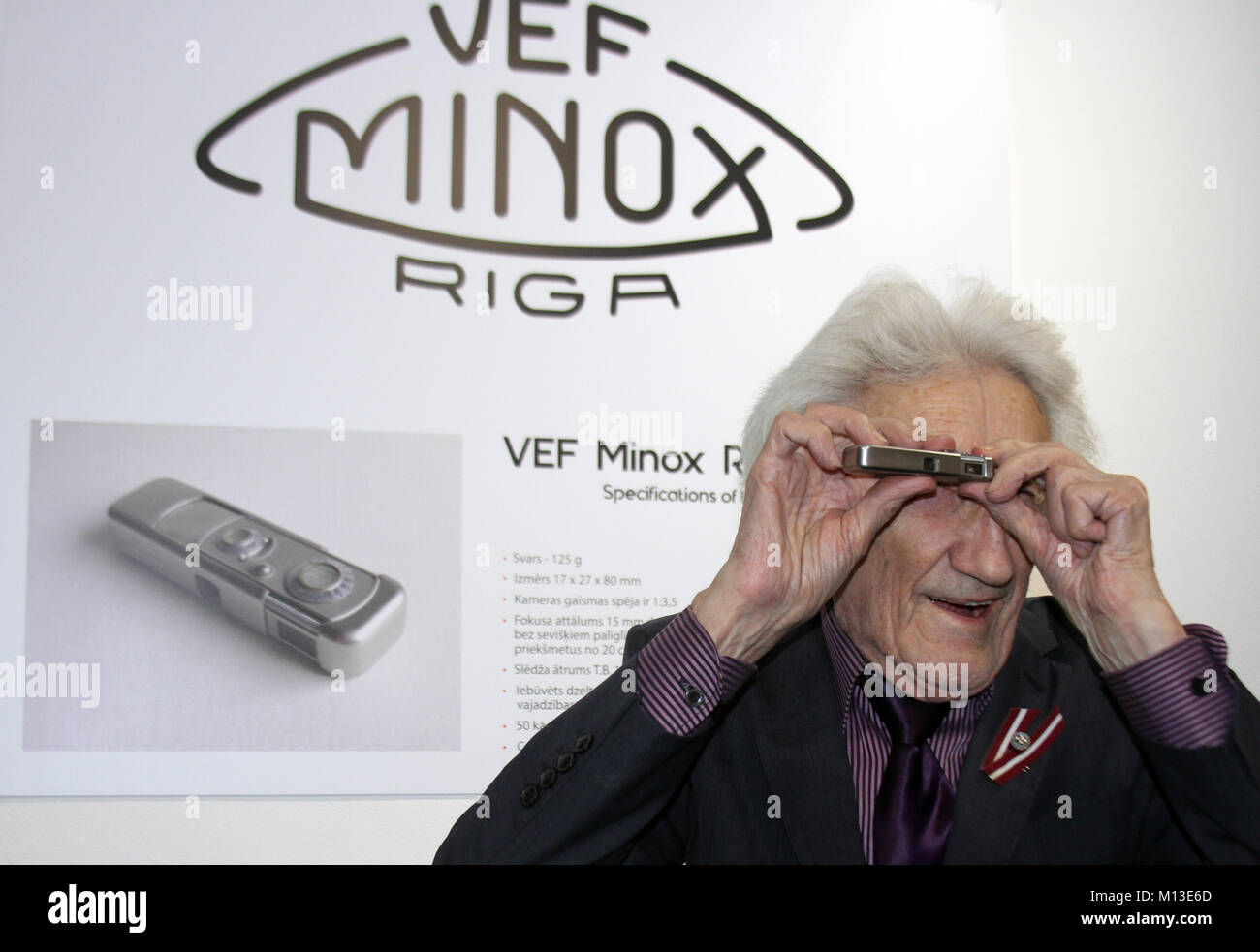 L'historien photo Peteris Korsaks article avec une caméra miniature Minox  devant une affiche pour l'exposition 'Le Monde avec Minox" au Musée letton  pour la photographie à Riga, l'Estonie, le 25 janvier 2018.