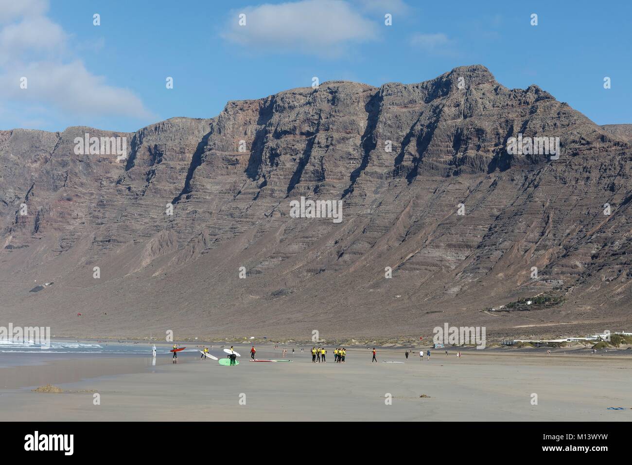 Espagne, Canaries, l'île de Lanzarote, Caleta de Famara, les surfeurs sur la plage de Famara avant le Risco de Famara cliff Banque D'Images