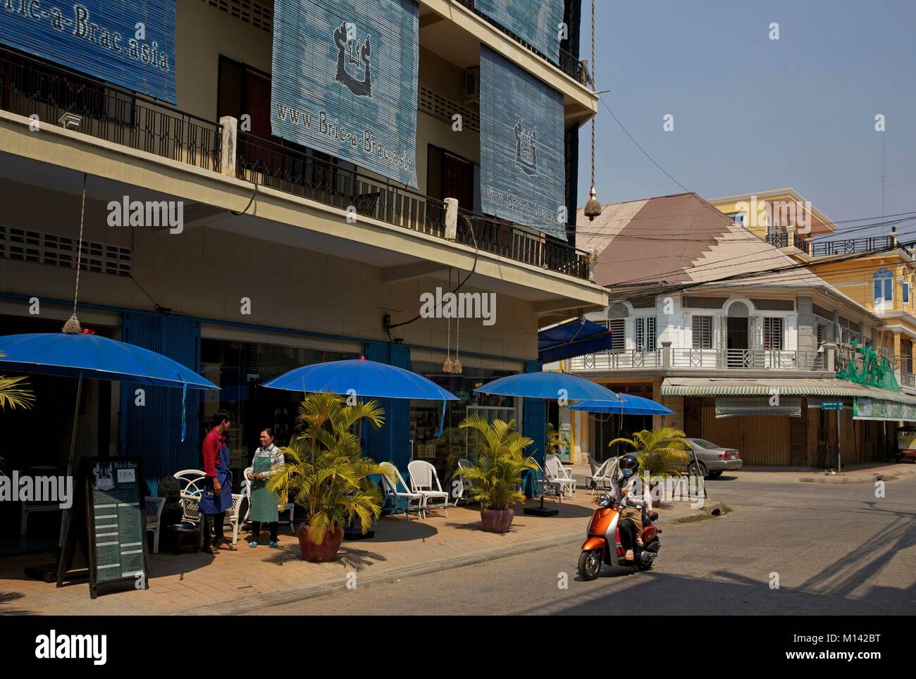 Cambodge, Battambang, femme et son babay en scooter devant la terrasse café à la bric-à-brac boutique de décoration Banque D'Images