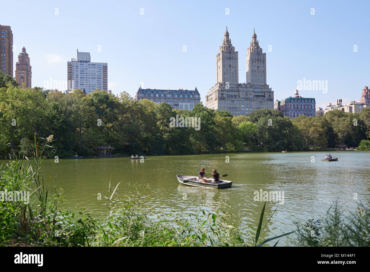 Étang de Central Park à New York avec des bateaux et le San Remo bâtiment dans une journée d'été Banque D'Images