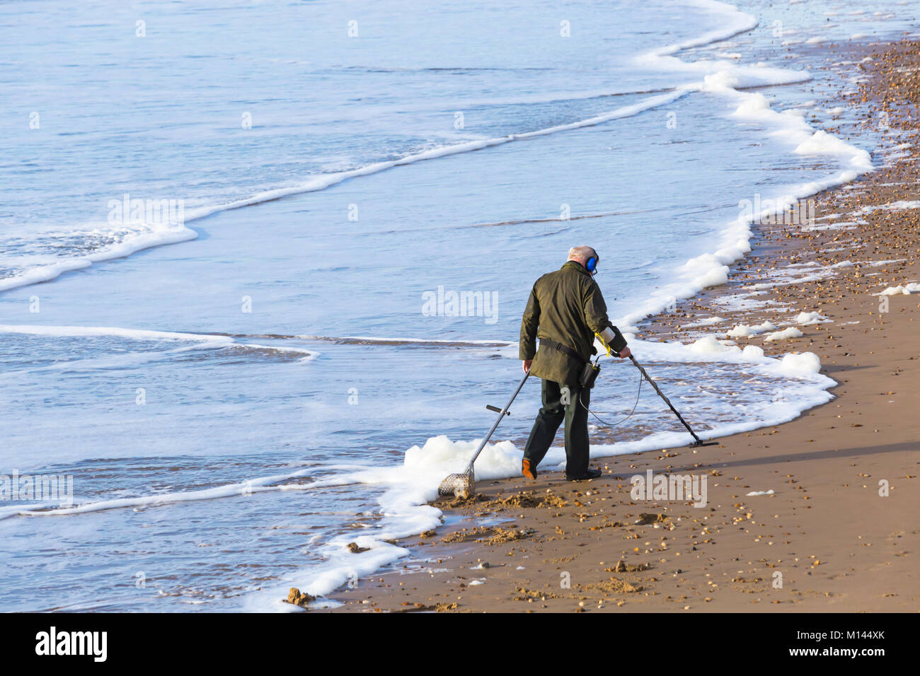 Beach Comber avec détecteur de métal à la recherche de trésors à la plage de Bournemouth, Bournemouth, Dorset UK en Janvier Banque D'Images