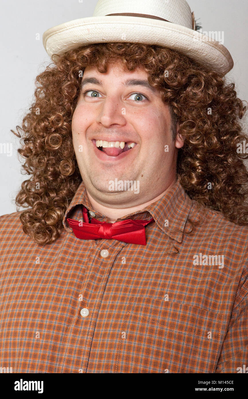 L'homme habillé dans un costume ridicule, avec une chemise à carreaux  rouge, noeud papillon, de long cheveux bouclés, un chapeau de paille et un  grand sourire Photo Stock - Alamy