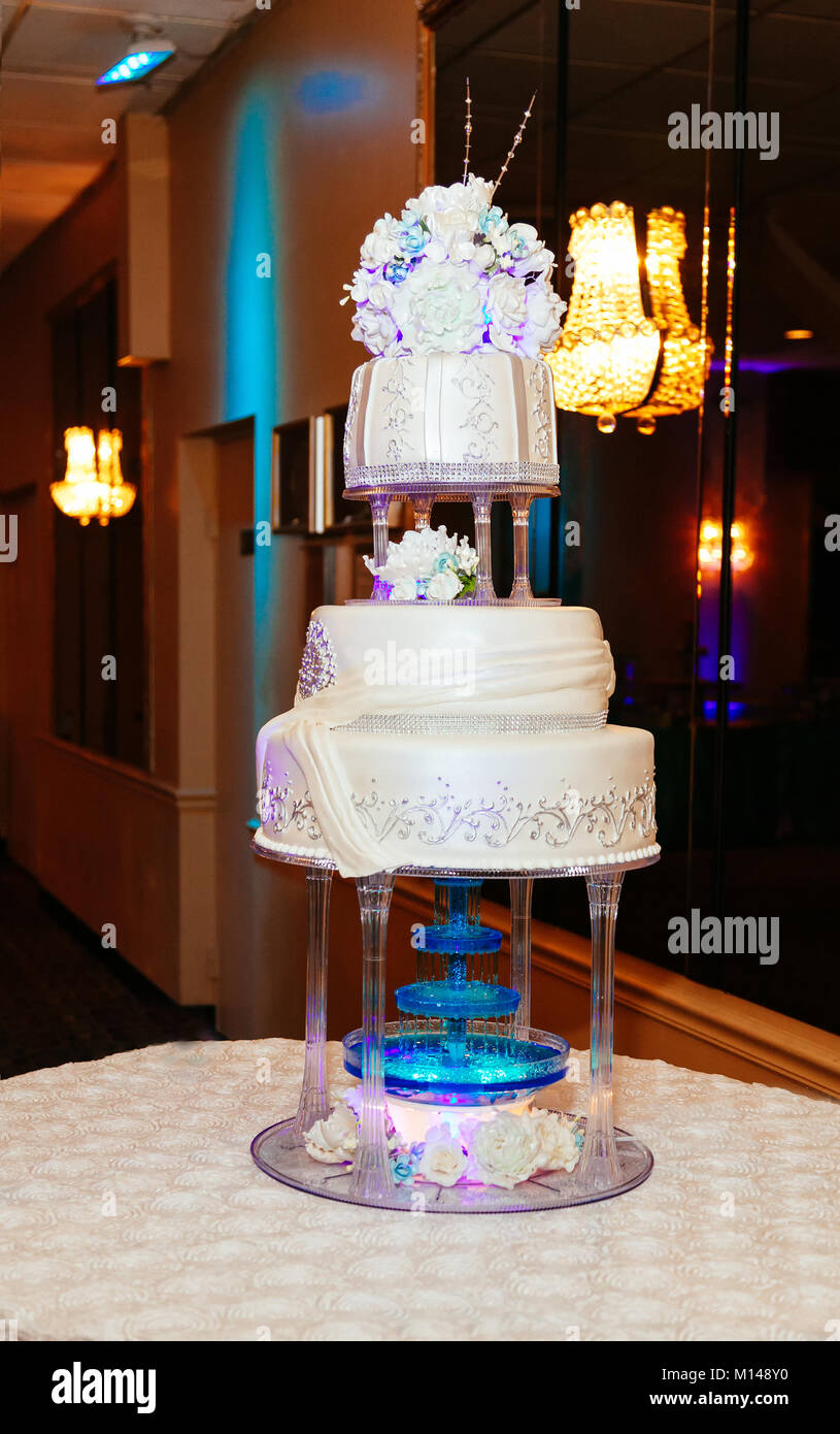 Un gâteau de mariage blanc multi de niveau sur une base en argent et des fleurs roses sur le dessus Banque D'Images