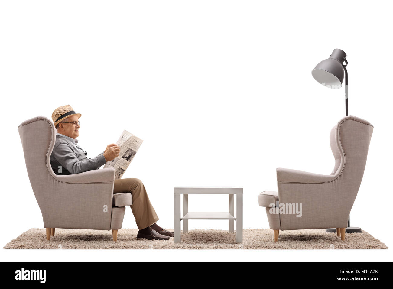 Homme mûr assis dans un fauteuil lisant un journal isolé sur fond blanc Banque D'Images