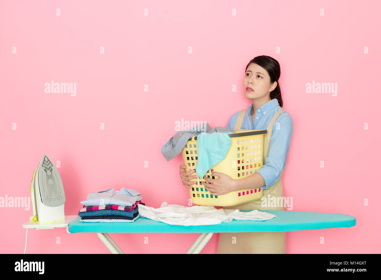 Femme de ménage tenue élégante malheureux panier de blanchisserie avec de  nombreux vêtements en désordre permanent fond rose à rêver Photo Stock -  Alamy