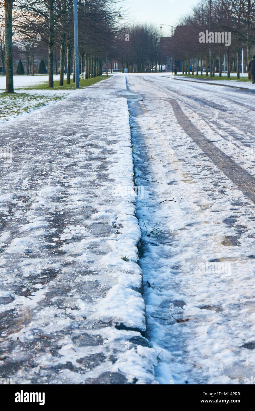 Route glacée et un trottoir recouvert de neige gelée. Banque D'Images