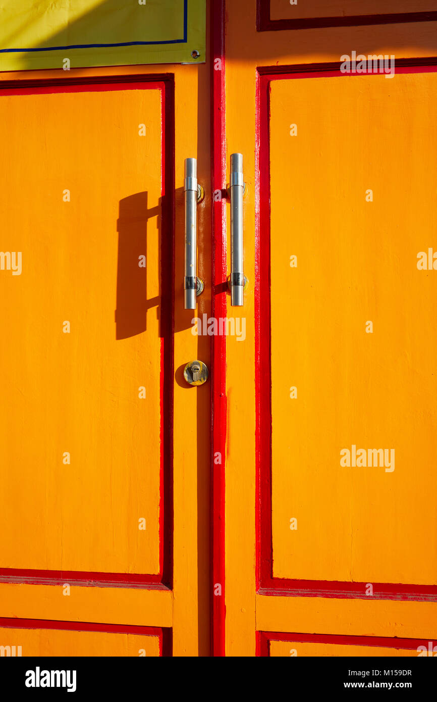 Fragment de porte en bois peint jaune avec poignées en métal. Yogyakarta, Java, Indonésie. Banque D'Images